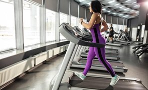 mulher na esteira da academia usando macacao fitness feminino